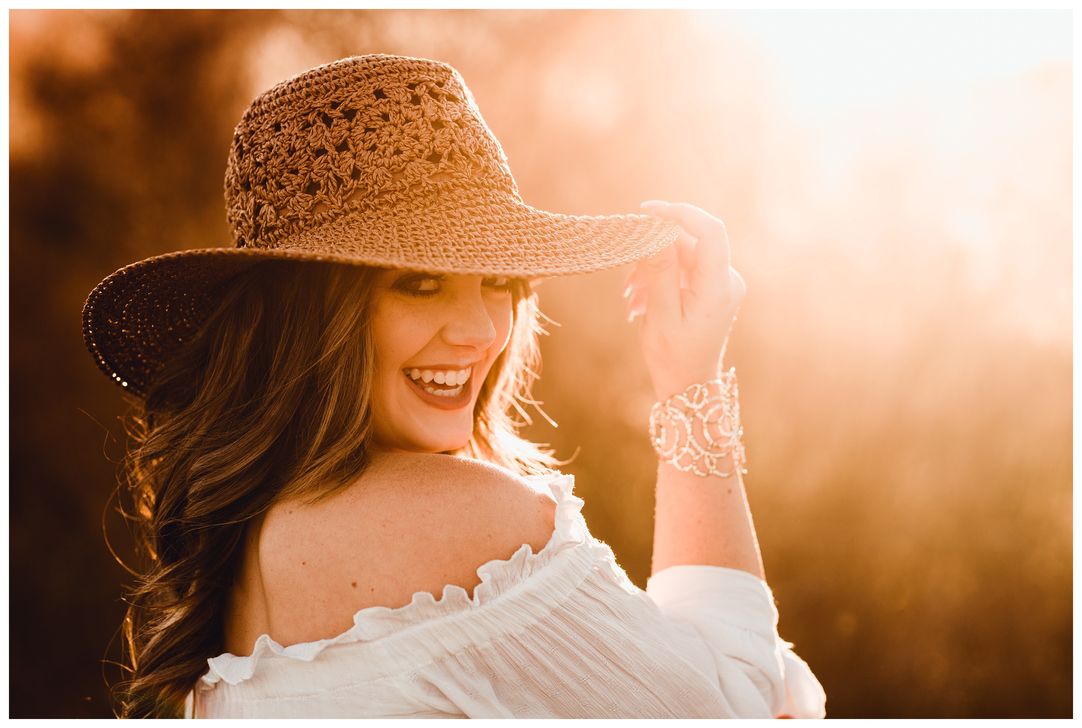 Southern senior girl takes photos in a field with a straw hat. Shelly Williams Photography