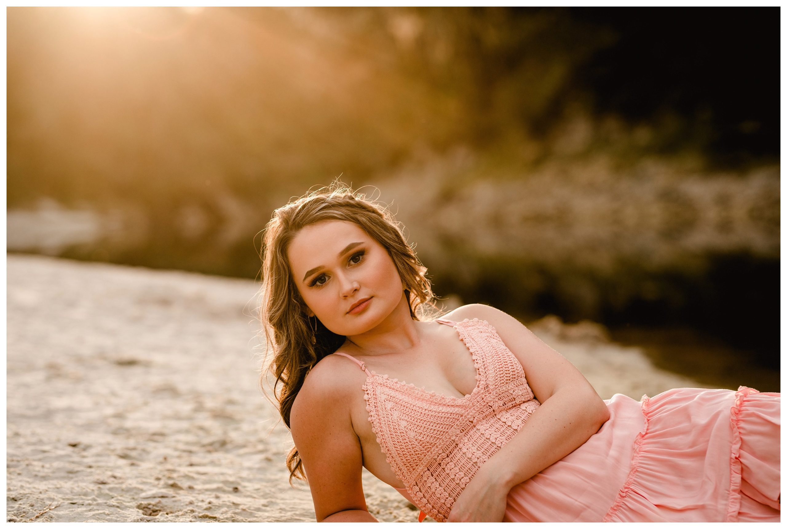 Senior pictures taken on the river with girl posed laying down.