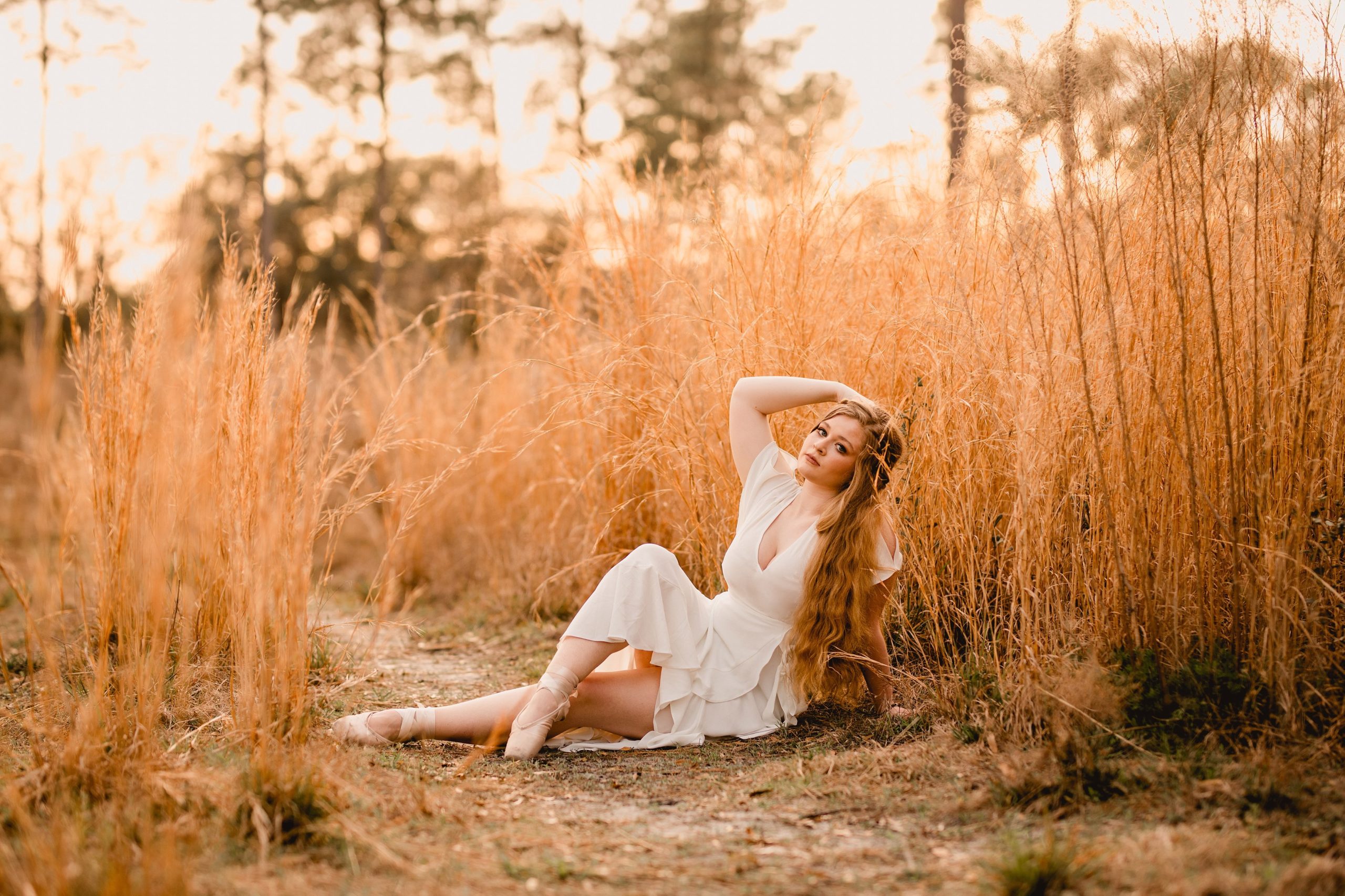 Dance senior pictures in north florida with tall grass and white dress. Pointe shoes.