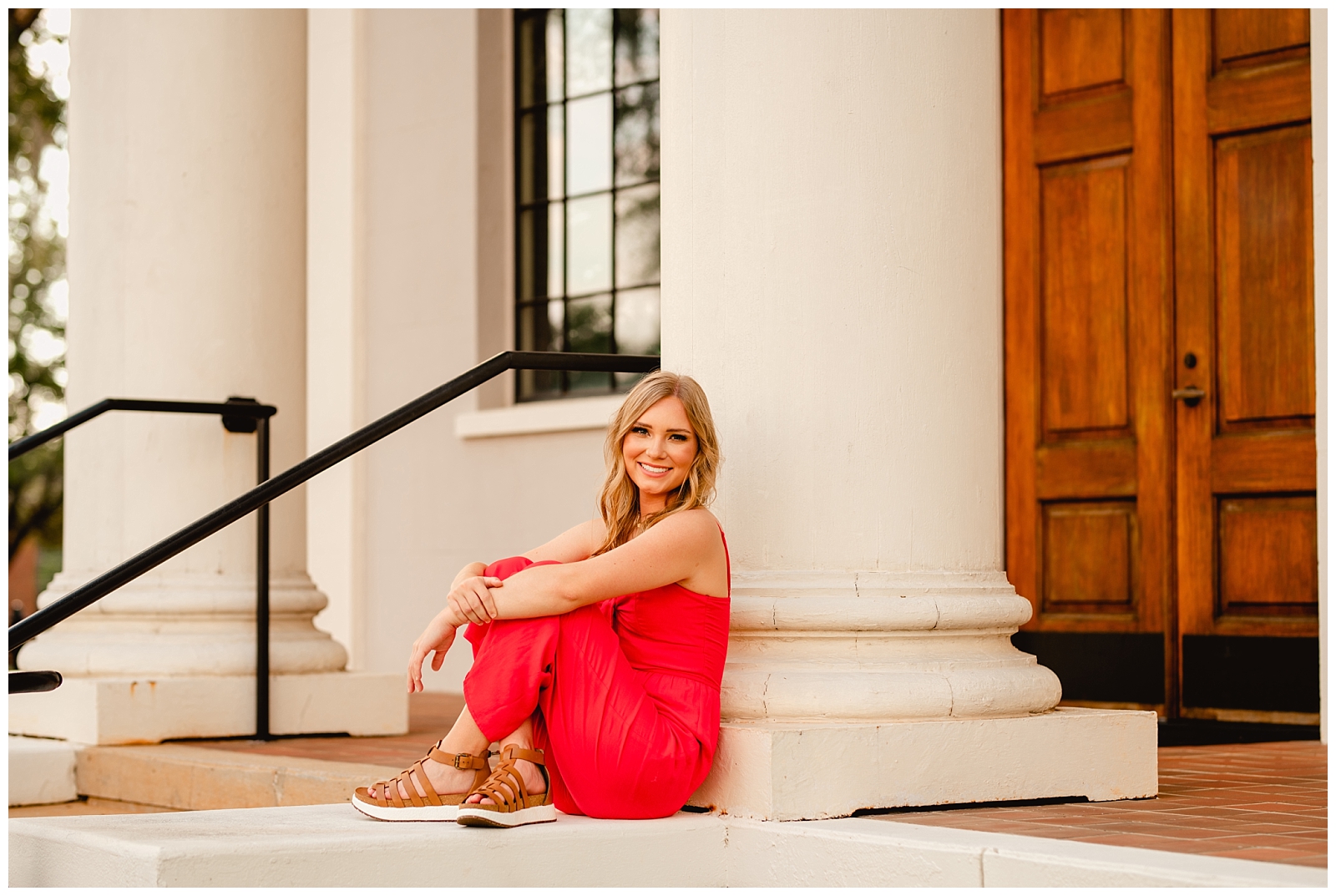 High School Senior takes pictures by old courthouse in bright red jumpsuit in Thomasville, Georgia.