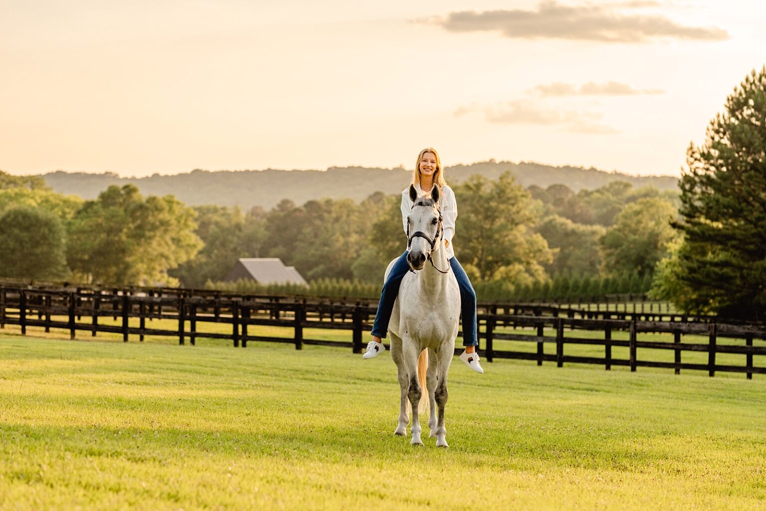 Professional horse photographer near Birmingham, Alabama takes photos of girl on her Dutch Warmblood jumper gelding at sunset with mountains on the horizon.