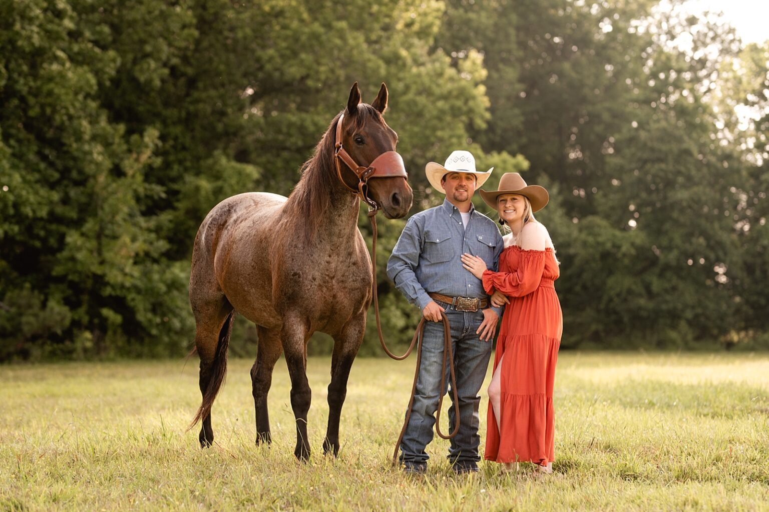 Western couple takes pictures together with roan gelding both wearing cowboy hats near Huntsville, AL.