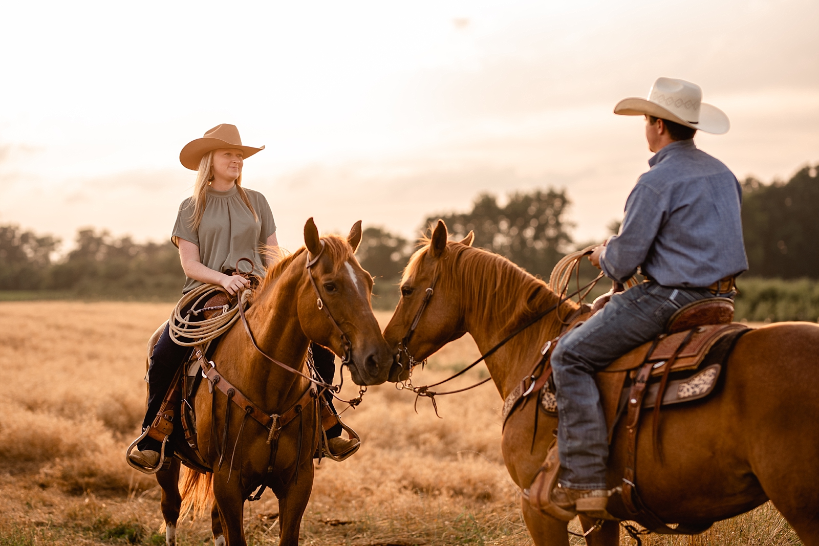Western couple takes pictures with their roping horses at sunset in a field. Couples posing ideas for cowgirl and cowboy.