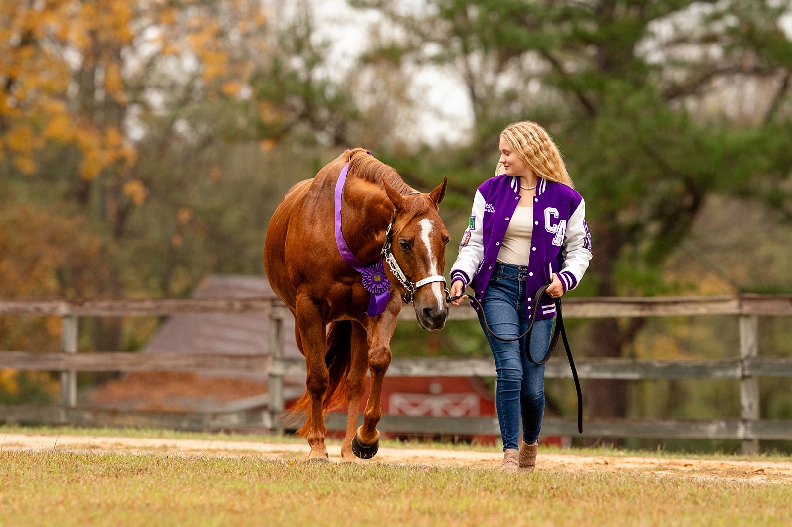 Allie wearing her letterman jacket during her equestrian-themed senior session in Alabama.